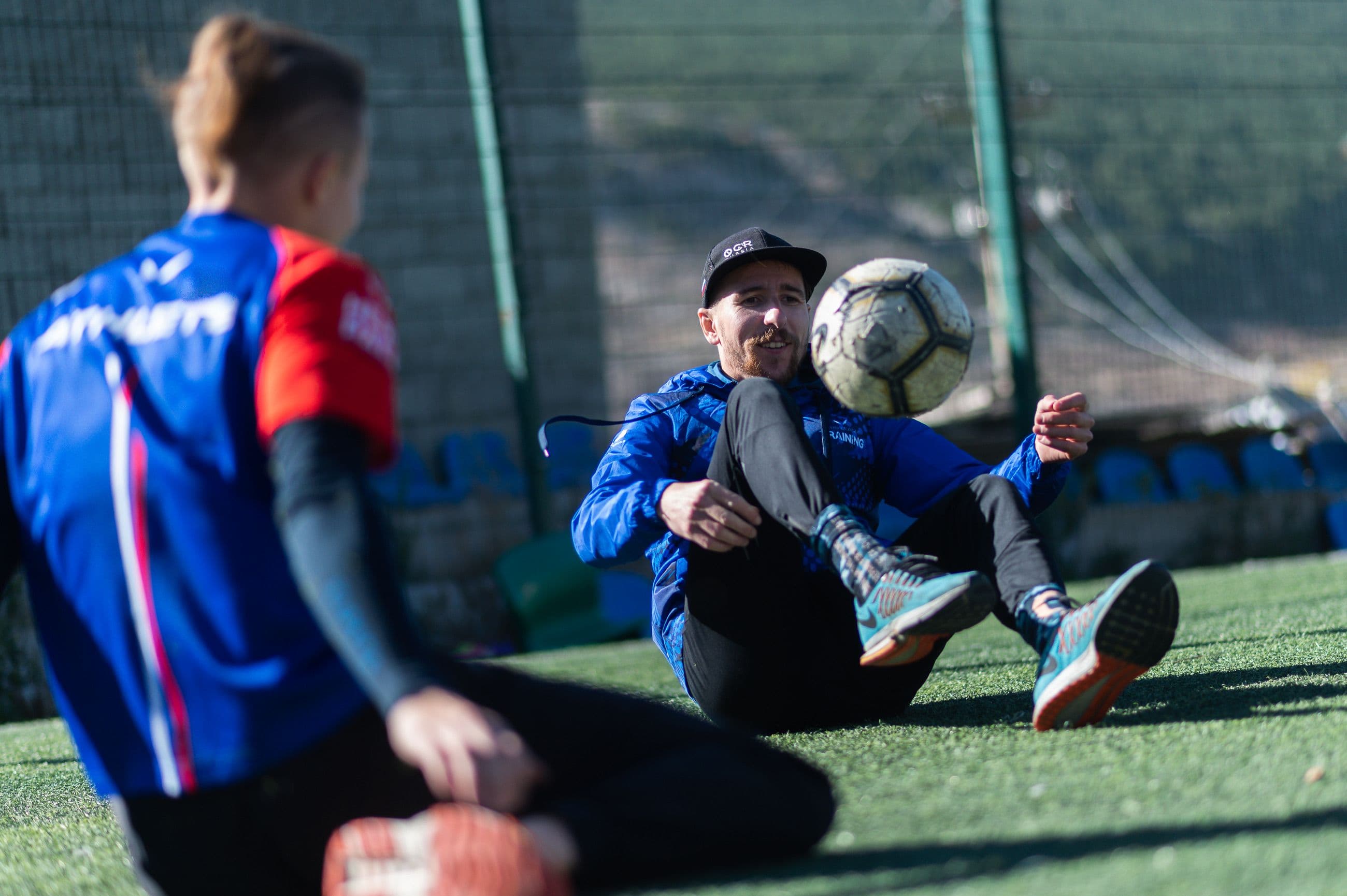 A coach guides a young footballer at sunrise